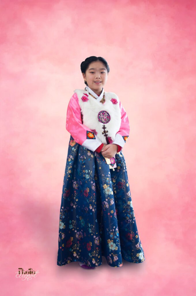 Teen Korean girl wearing traditional hanbok standing in front of a pink backdrop