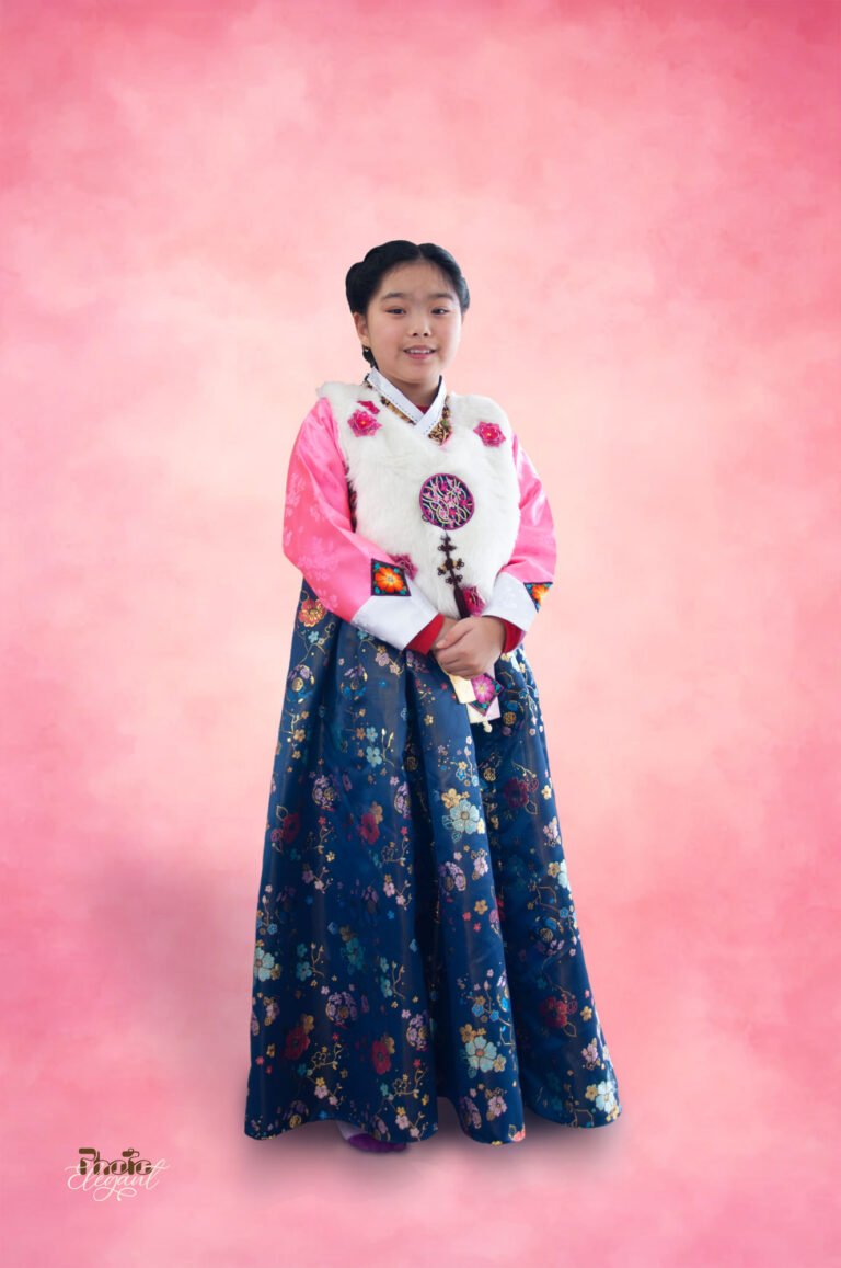 Teen Korean girl wearing traditional hanbok standing in front of a pink backdrop