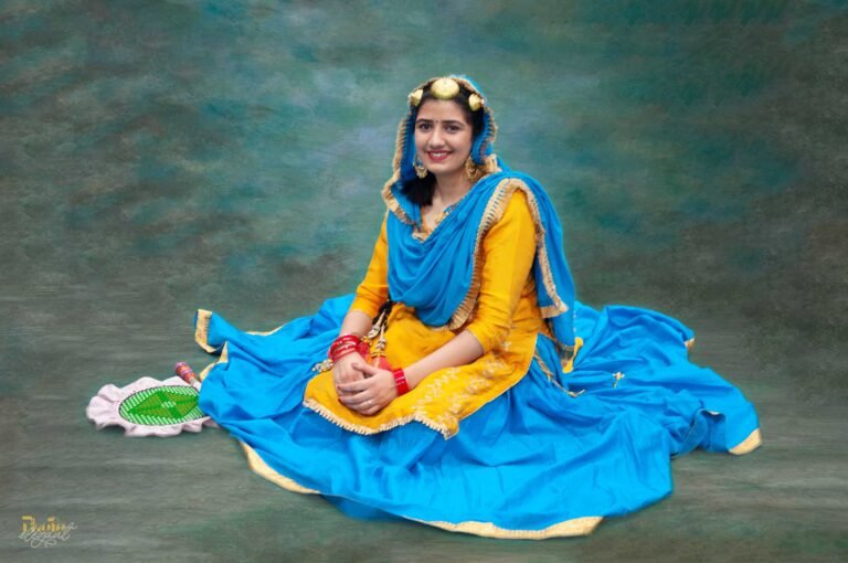 Girl in traditional Indian attire sitting gracefully on a turquoise backdrop in a professional studio setting