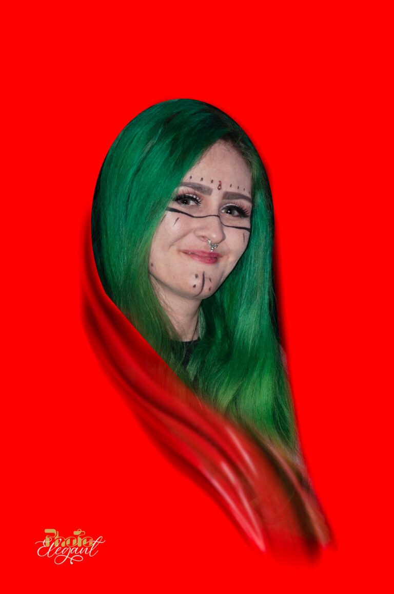 Young gypsy girl with green hair and facial tattoo standing in front of a bright red background