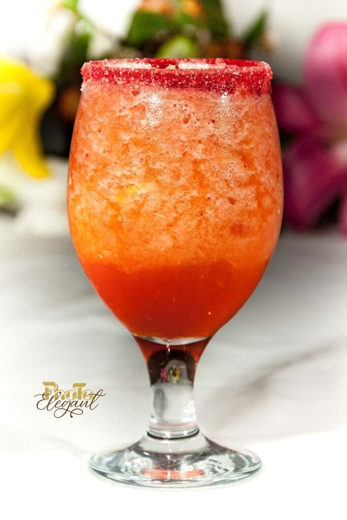Strawberry daiquiri in a hurricane glass garnished with a lime wedge